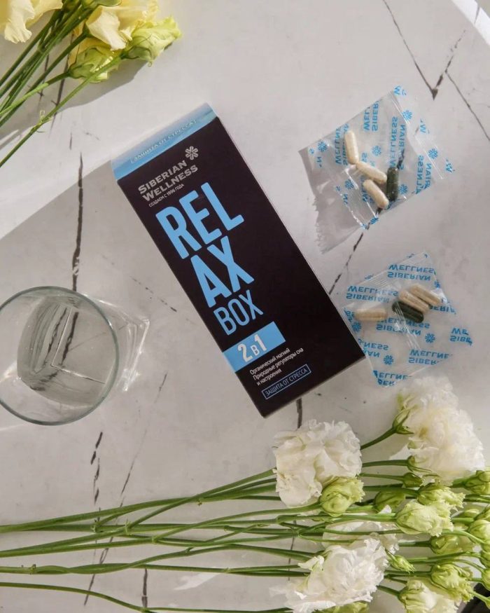 Relax box Siberian Wellness a stolu, pored se vide kesice sa po 3 kapsule u svakoj i malo niže je belo cveće